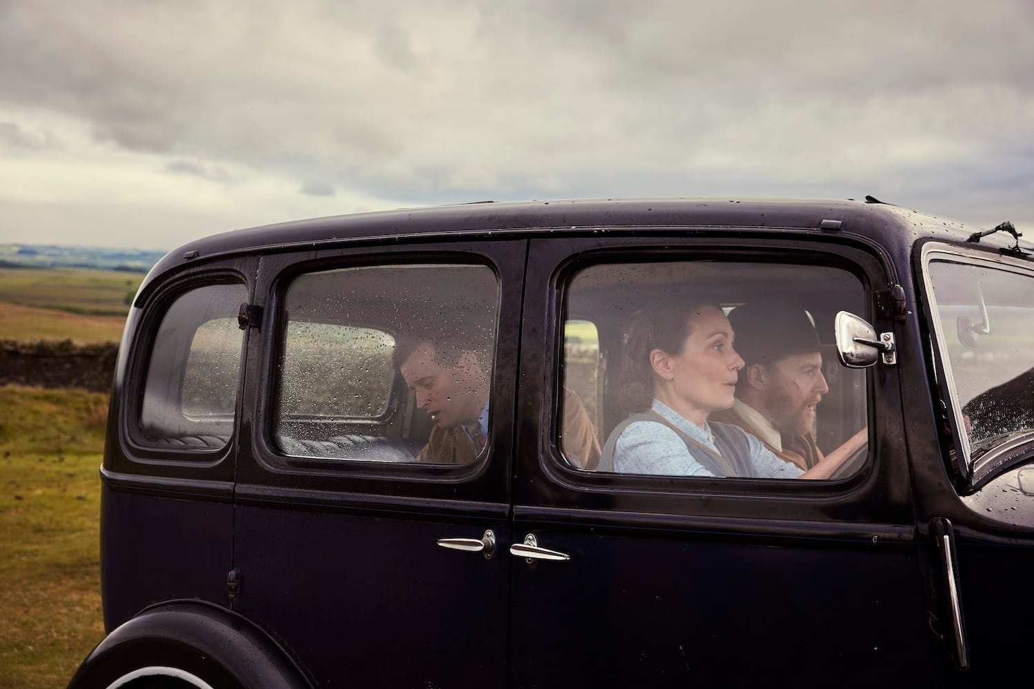 Audrey (Anna Madeley) drives like a fiend back to Darrowby with Siegfried (Samuel West) in the front seat while James (Nicholas Ralph) attends the sick dog in the back seat.