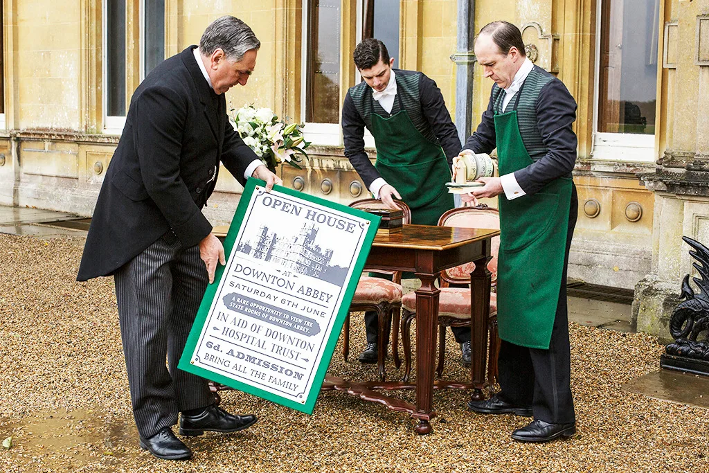 Carson (Jim Carter), Andy (Michael Fox) and Molesley (Kevin Doyle) setting up entrance sign and table.
