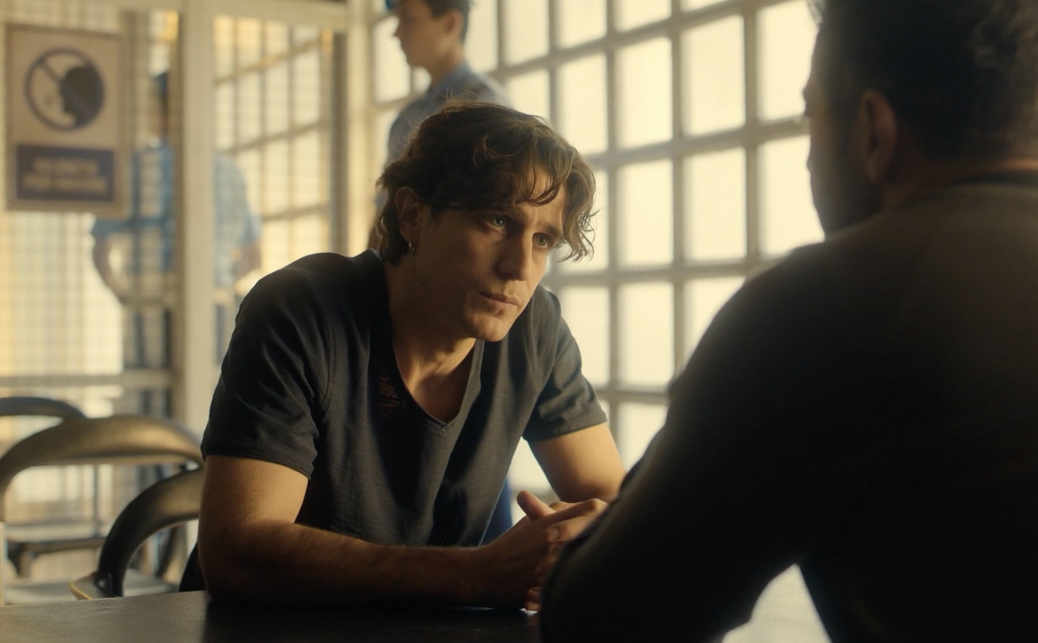 Luca (Alessandro Fella) talks to Joe in the jail, with guards in the background