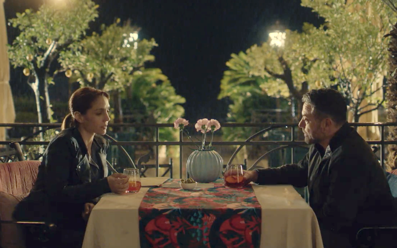 Joe (Warren Brown) and Lara (Cristiana Dell’Anna) drink and talk in the evening.