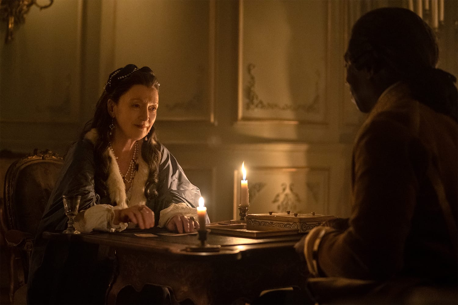 A quiet evening in with a friend. Genevieve (Lesley Manville) plays cards with Majordome (Hakeen Kae-Kazin).