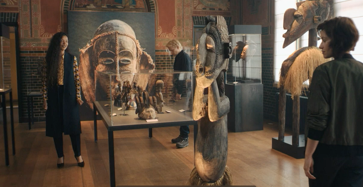 Museum director Christine Philips (Jaye Griffiths) shows Van der Valk (Marc Warren) and Lucienne Hassell (Mamie McCoy) the exhibit of Indonesian artifacts.