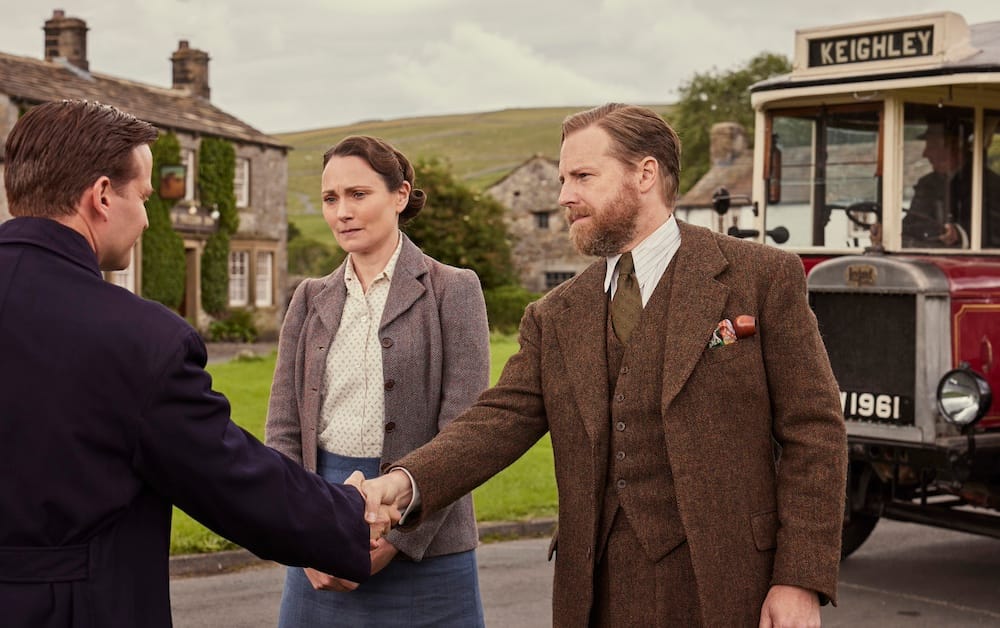 James (Nicholas Ralph) leaves for his service with the RAF and Siegfried (Samuel West) and Mrs. Hall (Anna Madeley) see him off at the bus stop.
