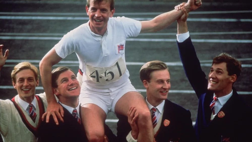 British team members Nigel Havers (Lord Andrew Lindley), Nicholas Farrell (Monty), Henry Stallard (Daniel Gerroll), and Harold Abrahams (Ben Cross) celebrate Eric Liddell's (Ian Charleston) gold medal.