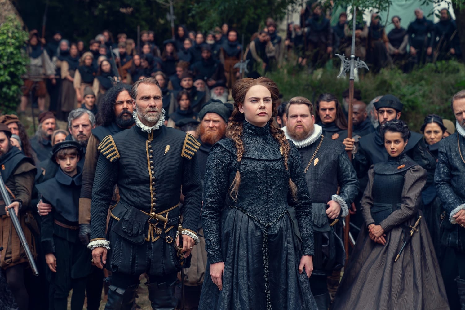 Edith (Isobel Jesper Jones) stands with Montmorency (Alexandre Willaume), Louis de Bourbon (Danny Kirrane) and Aabis (Amrita Acharia), surrounded by Edith's followers.