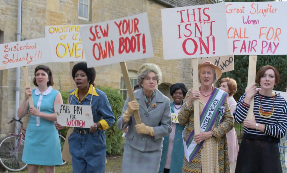 On the picket line, Bernice McDowell (Dani Moseley), Mrs. Clam (Belinda Lang), Miss Thimble (Sarah Crowder), and Pamela Millington (Grace Molony).