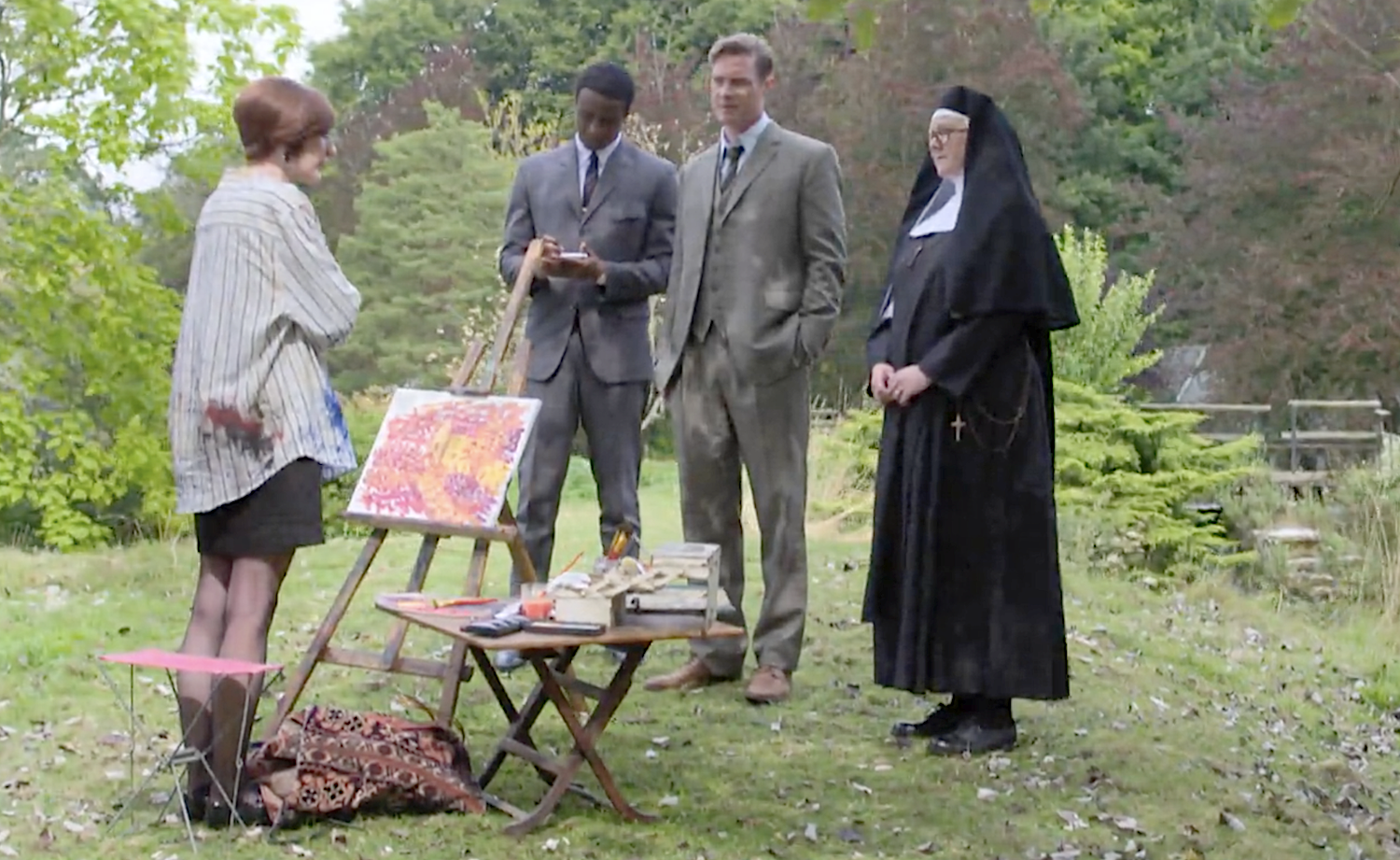 DI Sam Gillespie (Max Brown), DS Felix Livingstone (Jerry Iwu), and Sister Boniface (Lorna Watson) interview Pamela Millington (Grace Molony) while she paints.