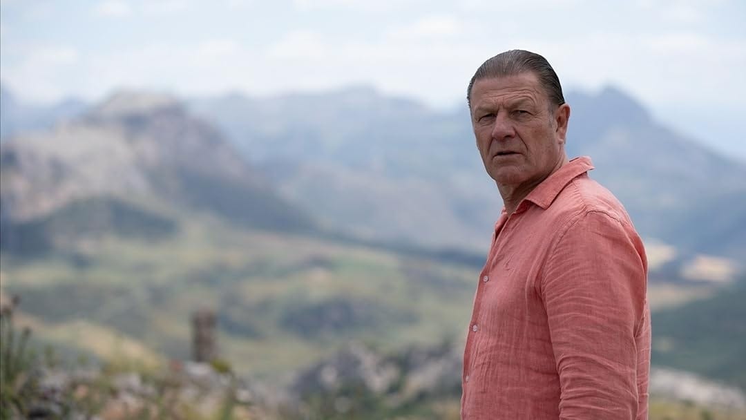 Ronnie Phelan (Sean Bean) stands in a rocky Spanish landscape.